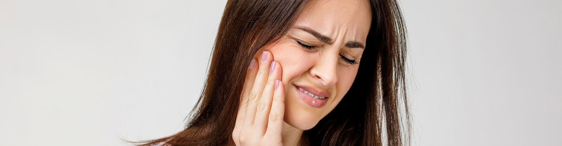 Woman holding her cheek in pain.